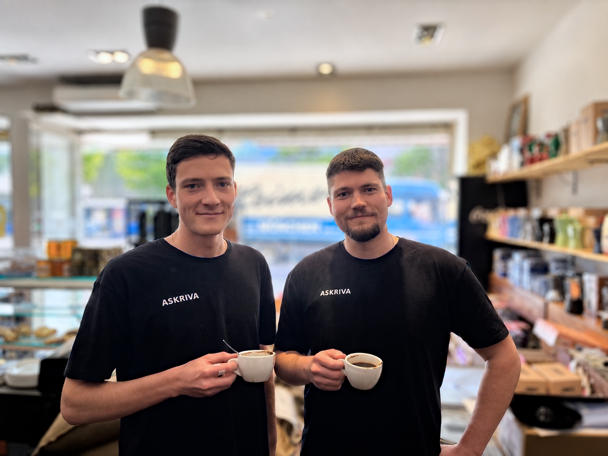Die beiden Gründer von Askriva, Alex und Eric. Abgebildet in einer Rösterei mit einer Kaffeetasse in der Hand.
